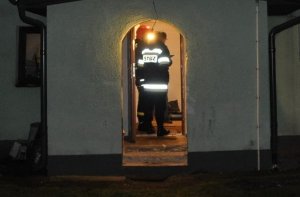Strażacy stoją w wejściu do domu