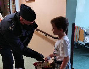 policjant wręcza dziecku prezent