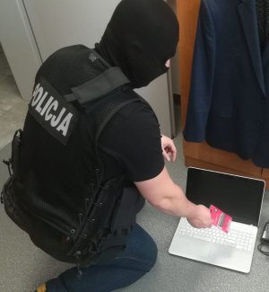 policjant kryminalny w kominiarce  i odzyskany laptop