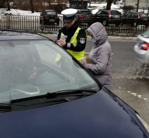 kontrola drogowa. na zdjęciu policjantka, kobieta w kurtce oraz samochód