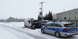 Oznakowany policyjny radiowóz za którym po prawej stronie na poboczu drogi znajduje się rozbity pojazd marki Renault oraz po.jpg
