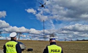 Policjanci sterują dronem w powietrzu.