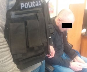 siedzący zatrzymany, obok niego policjant