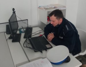 policjant z drogówki siedzi przed komputerem podczas lekcji on-line