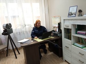 policjantka siedzi w pokoju przed komputerem i prowadzi zdalną lekcję z uczniami