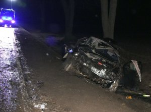Całkowicie rozbity po wypadku pojazd alfa romeo, w tle policyjny radiowóz