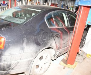 bok samochodu osobowego i stojący obok podnośnik kolumnowy