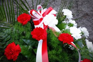 Wieniec z kwiatami koloru białego i czerwonego z wstążką koloru Polskiej flagi.