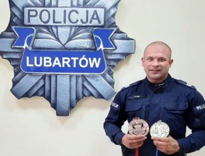 umundurowany policjant trzyma w ręce dwa medale