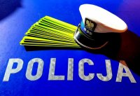 policyjna czapka i odblaski na niebieskim tle z napisem Policja