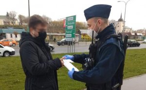 policjant rozdaje maseczkę nastolatkowi na chodniku w Lublinie