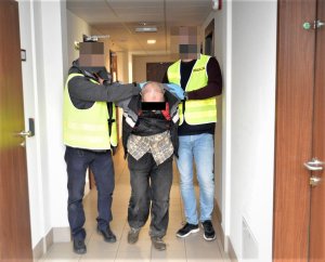 zatrzymany mężczyzna prowadzony do celi przez dwóch policjantów