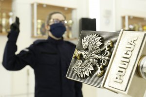policjantka składa ślubowanie, w tle metalowa część sztandaru z napisem Policja