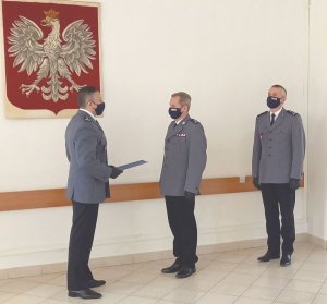 Wprowadzenie Komendanta Powiatowego w Janowie Lubelskim, trzech policjantów stoi na tle polskiego godła