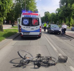 rower leżący na ulicy w tle karetka granatowy ford policjant i dwoje ludzi