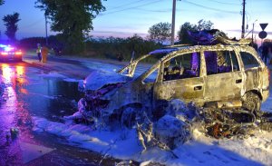 Zdjęcie spalonego samochodu i motocykla w tle policja i osoby