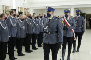 Przemarsz pocztu sztandarowego przed funkcjonariuszami policji.