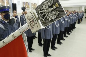 W pierwszym planie zdjęcia grot sztandaru Komendy Wojewódzkiej Policji w Lublinie na nim umieszczony jest wizerunek orła ustalony dla godła Rzeczypospolitej Polskiej z napisem KWP LUBLIN.
W drugim planie zdjęcia stoją funkcjonariusze policji do odznaczenia.