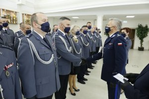 Komendant Wojewódzki Policji w Lublinie odznacza funkcjonariusza medalem. Po prawej stronie zdjęcia Wojewoda Lubelski trzyma legitymację, którą za chwilę wręczy.