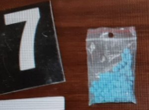 niebieskie tabletki w woreczku obok kartonik z cyfrą 7