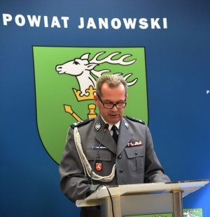 Święto Policji w janowskiej komendzie. Komendant przemawia na tle herbu miasta.