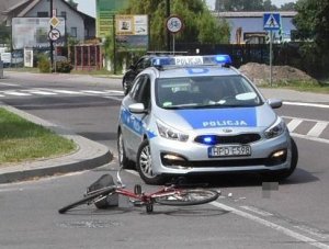 rower leżący na drodze, w tle radiowóz