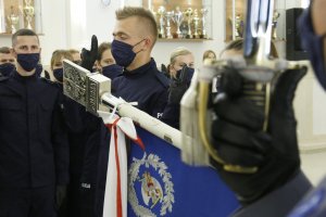 Grot sztandaru Komendy Wojewódzkiej Policji w Lublinie w drugim planie ślubujący policjanci.