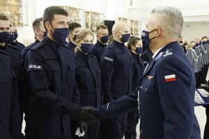 Komendant Wojewódzki Policji wręcza legitymację nowemu funkcjonariuszowi.