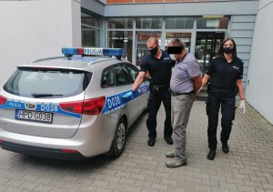 złodziej rowerów w asyście policjantów , założone kajdanki, wsadzany do radiowozu Kia