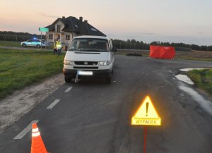 oznakowane miejsce wypadku drogowego, stojący na jezdni samochód marki Volkswagen, stojący na jezdni czerwony parawan z napisem Straż, w tle policjanci