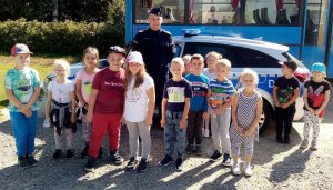 policjant z dziećmi na tle radiowozu i autobusy szkolnego