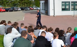 policjant w czasie spotkania z siedzącymi na trawie uczniami ze szkoły w Miączynie