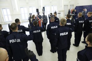 Policjanci ślubują na Sztandar Komendy Wojewódzkiej Policji w Lublinie. Na zdjęciu widać nowych funkcjonariuszy w granatowym moro z napisem policja.