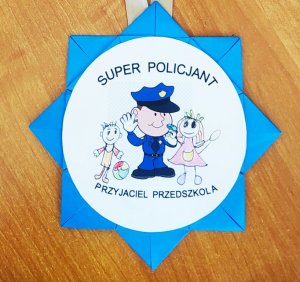zdjęcie przedstawia własnoręcznie wykonany papierowy medal w kolorze niebieskim który dzieci podarowały policjantom