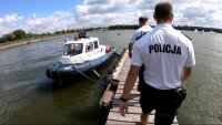 Policjanci idą pomostem do łodzi policyjnej nad Zalewem Zemborzyckim.