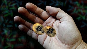 Dwie monety bitcoin trzymane w dłoni.