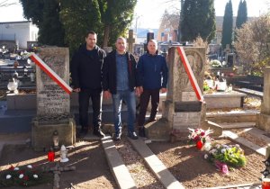 trzech policjantów stoi przy grobach