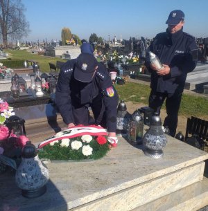 policjanci kładą wiązankę na grobie zmarłego policjanta