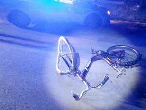 zdjęcie w nocy. na drodze leży rozbity rower. w tle widać policyjny radiowóz