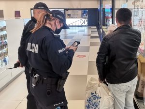 Policjanci legitymują osobę w centrum handlowym