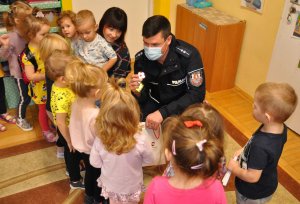 Policjant wręcza przedszkolakom odblaski