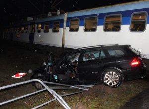 pora po zmroku, widoczny pociąg osobowy oraz uszkodzony samochód osobowy z nadwoziem kombi koloru ciemnego
