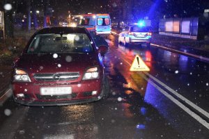 pora po zmroku widoczne opady zaparkowany samochód osobowy marki opel koloru bordowego na drugim palnie radiowóz policji i karetka pogotowia