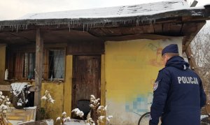 policjant obok opuszczonego domu