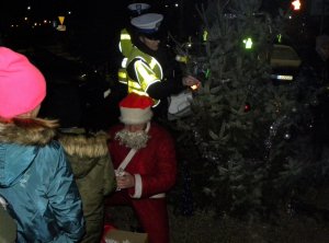 policjanci Wydziału Ruchu Drogowego stojący przy choince, obok dzieci i Święty Mikołaj