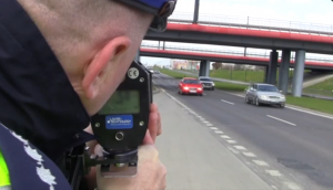 policjant z drogówki mierzy prędkość pojazdów na drodze