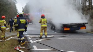 paląca się ciężarówka i strażacy podczas akcji ratowniczo - gaśniczej