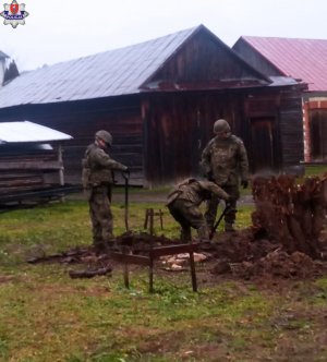 wojskowy trzyosobowy patrol saperski podczas sprawdzania terenu działki pod kątem zakopanych w ziemi niewybuchów