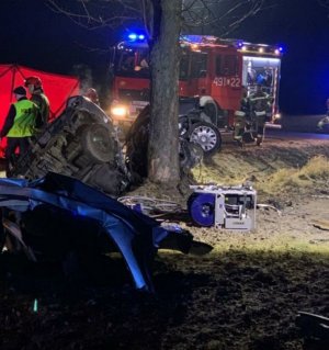 rozbity pojazd w tle policjant strażak i wóz strażacki