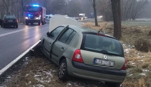 stojący na poboczu pojazd marki Renault z uszkodzonym przodem  w tle uszkodzony pojazd marki Audi i pojazd straży pożarnej